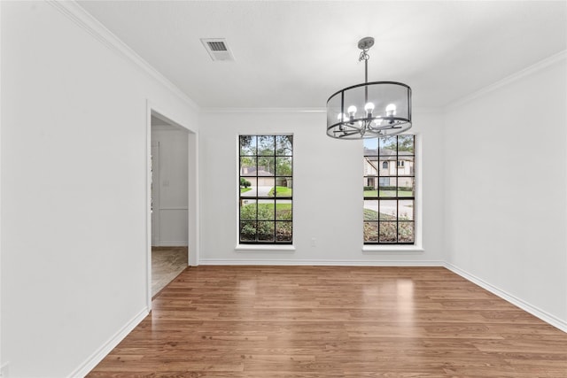 unfurnished dining area featuring an inviting chandelier, hardwood / wood-style flooring, and ornamental molding