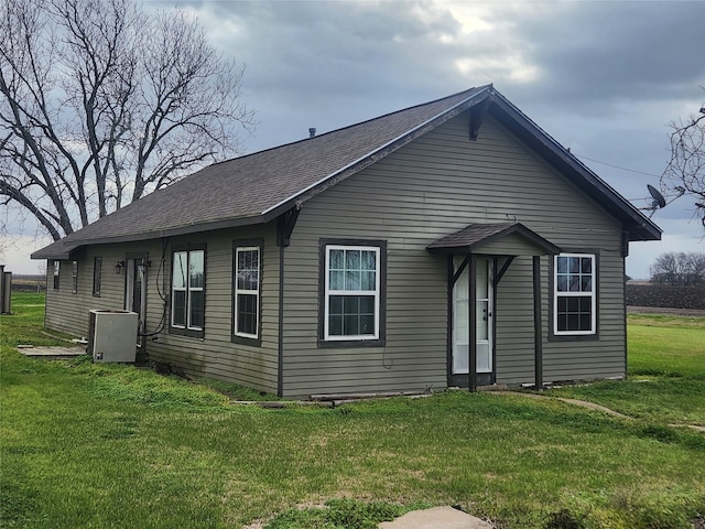 view of front of house featuring a shingled roof and a front lawn