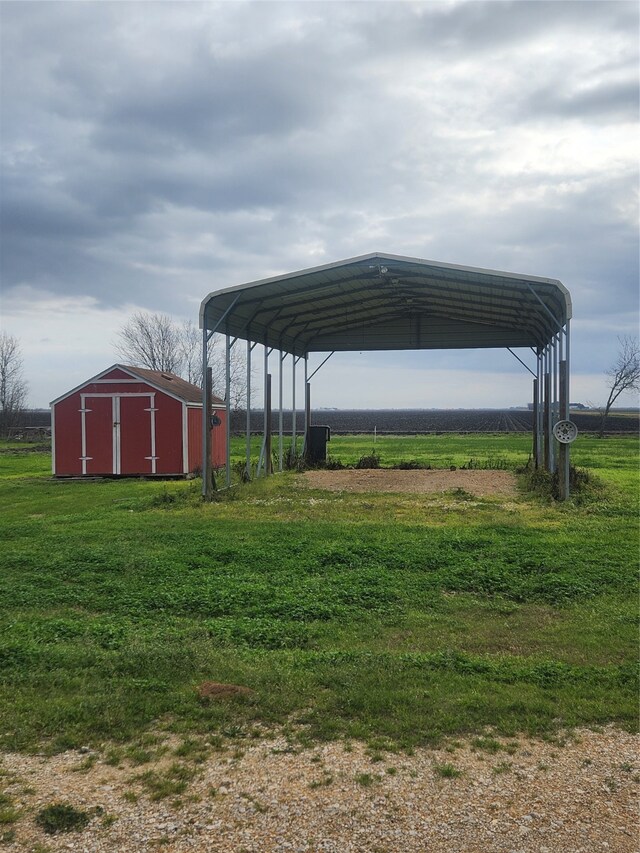 view of parking featuring a detached carport, a rural view, driveway, and a shed