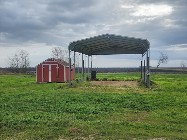 exterior space featuring driveway, a storage shed, an outbuilding, a rural view, and a detached carport