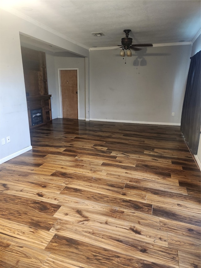 spare room featuring a fireplace, wood finished floors, visible vents, a ceiling fan, and ornamental molding