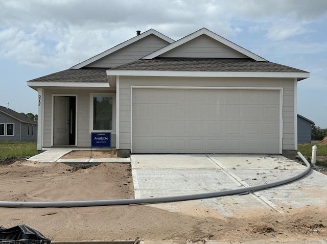 ranch-style house featuring concrete driveway, an attached garage, and a shingled roof