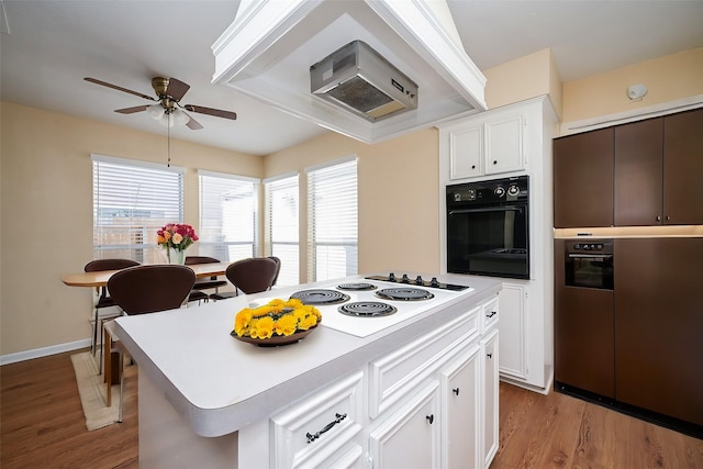 kitchen featuring light hardwood / wood-style flooring, oven, white cabinetry, a kitchen island, and white electric stovetop