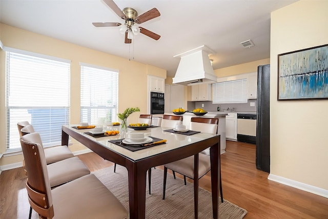 dining space featuring ceiling fan, sink, a healthy amount of sunlight, and light hardwood / wood-style flooring