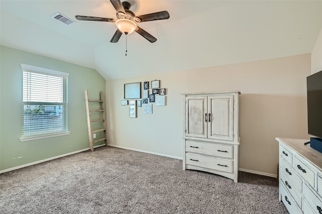 unfurnished bedroom with lofted ceiling, ceiling fan, visible vents, baseboards, and dark carpet