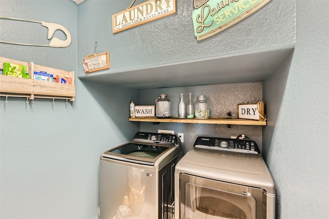 washroom featuring laundry area, a textured wall, and washing machine and clothes dryer