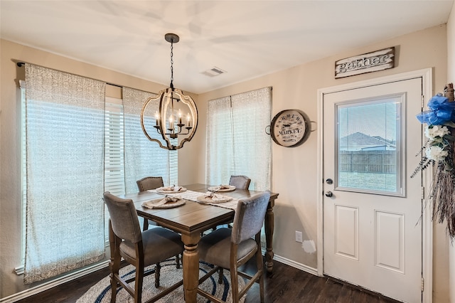 dining area featuring dark wood-type flooring, visible vents, a notable chandelier, and baseboards