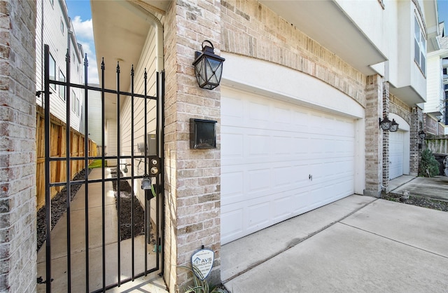 garage featuring driveway and a gate