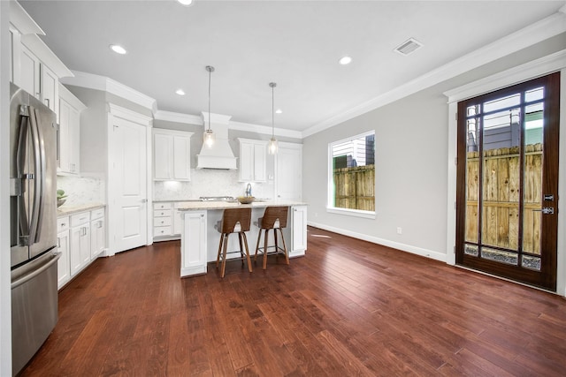 kitchen featuring visible vents, stainless steel fridge with ice dispenser, a center island, hanging light fixtures, and white cabinetry