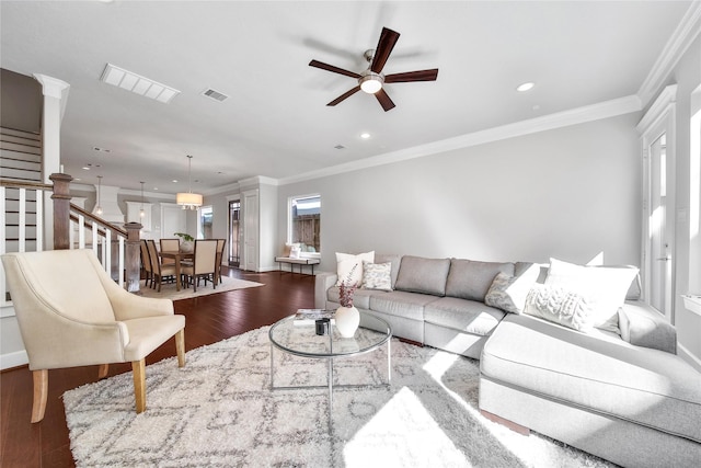 living area featuring crown molding, visible vents, dark wood finished floors, and stairway