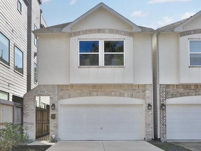 multi unit property featuring brick siding, driveway, an attached garage, and stucco siding