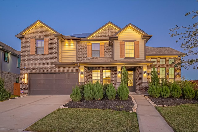 view of front of home featuring an attached garage, brick siding, solar panels, and concrete driveway