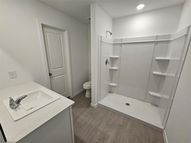 bathroom featuring toilet, vanity, walk in shower, and wood-type flooring