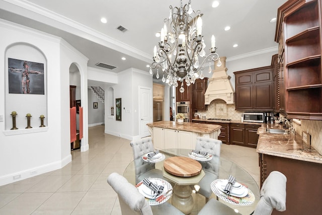 tiled dining space featuring a notable chandelier, ornamental molding, and sink