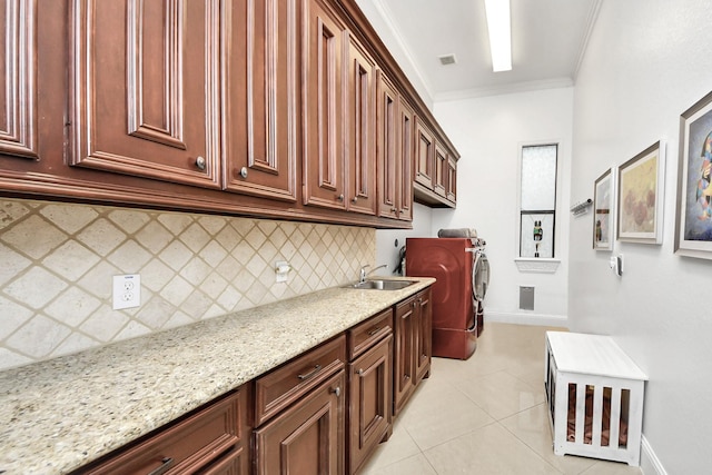 laundry area featuring cabinets, sink, ornamental molding, light stone counters, and light tile patterned floors