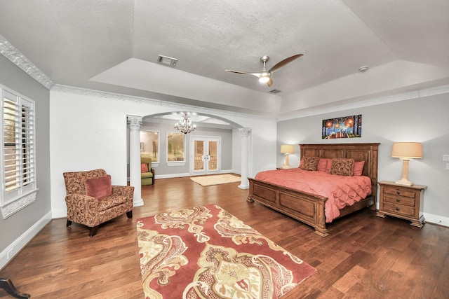 bedroom with a textured ceiling, french doors, a raised ceiling, dark hardwood / wood-style flooring, and ornate columns