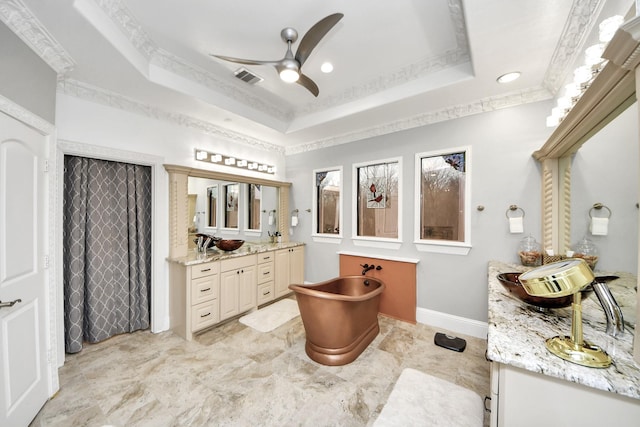 bathroom with ceiling fan, a tray ceiling, vanity, and ornamental molding