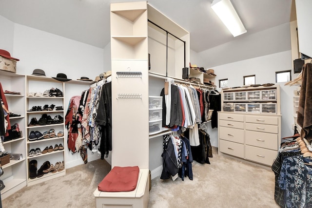 walk in closet with light carpet and lofted ceiling