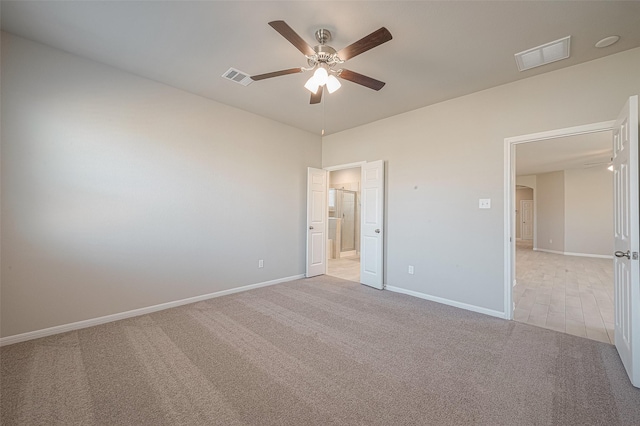 unfurnished bedroom featuring light colored carpet, ceiling fan, and ensuite bath