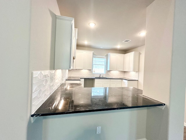 kitchen featuring white cabinets, sink, backsplash, and kitchen peninsula