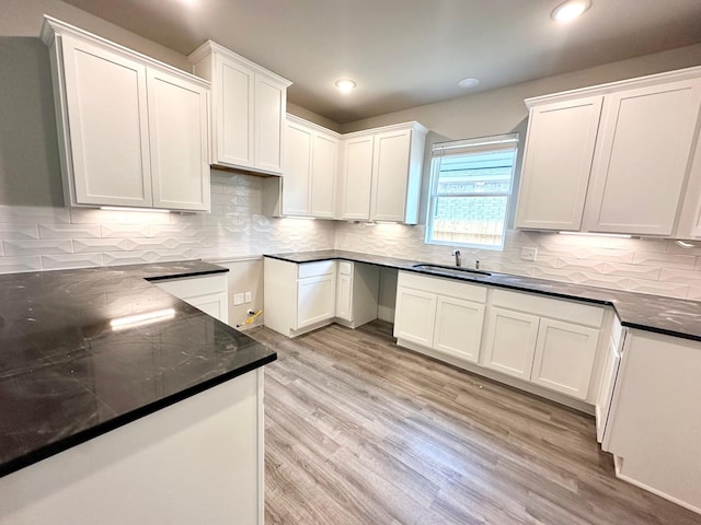 kitchen with light hardwood / wood-style floors, white cabinetry, sink, and backsplash