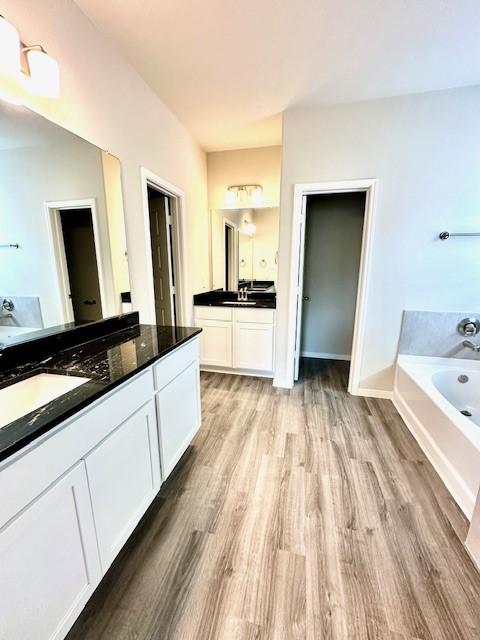 bathroom featuring hardwood / wood-style flooring, vanity, and a tub to relax in