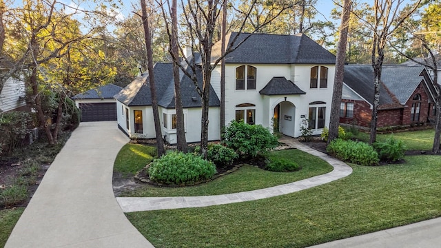 view of front of property featuring a front lawn, a garage, and an outbuilding