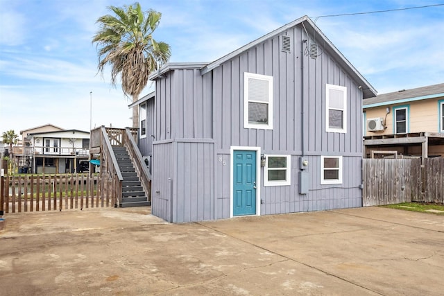 exterior space featuring board and batten siding, a patio area, fence, and stairway