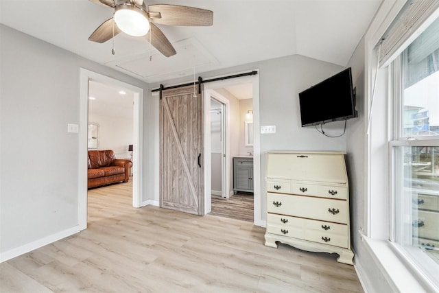 bedroom with a barn door, baseboards, lofted ceiling, ceiling fan, and light wood-type flooring