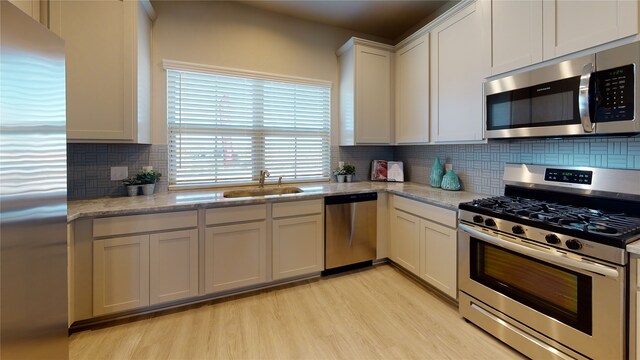 26356 Cooperstown Way, Splendora, TX 77372 - kitchen with backsplash, light wood-style flooring, stainless steel appliances, white cabinetry, and a sink