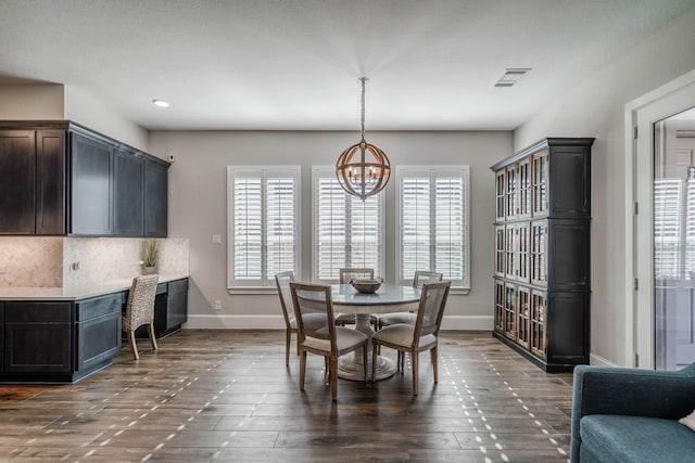 dining room with visible vents, dark wood finished floors, a notable chandelier, and baseboards