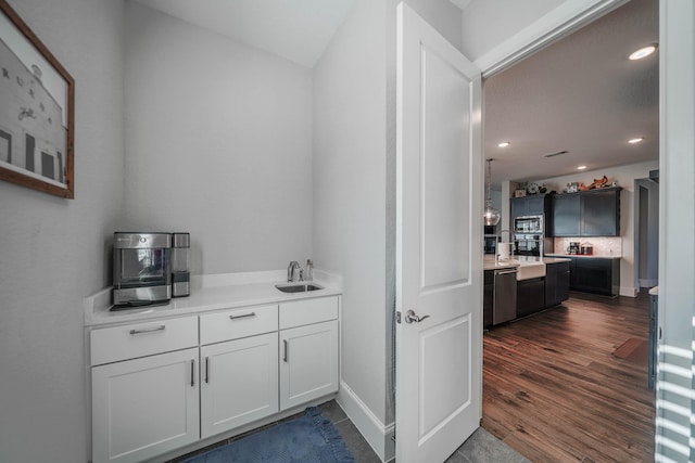 bar with recessed lighting, stainless steel appliances, a sink, baseboards, and dark wood finished floors