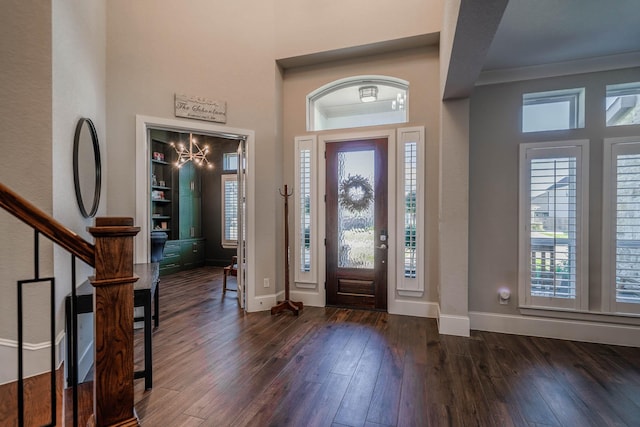 foyer entrance featuring dark wood-type flooring, a healthy amount of sunlight, ornamental molding, and baseboards