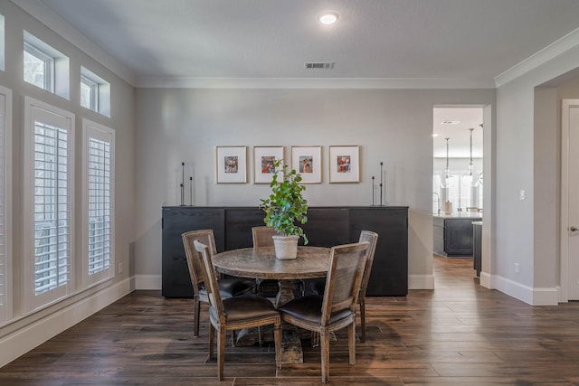 dining room with dark wood-style flooring, visible vents, and crown molding