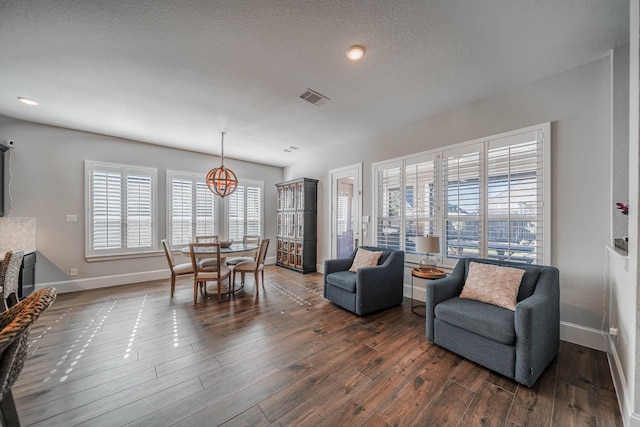 living room with baseboards, visible vents, dark wood-style flooring, a textured ceiling, and a notable chandelier