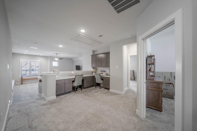 home office featuring light carpet, attic access, visible vents, baseboards, and built in study area