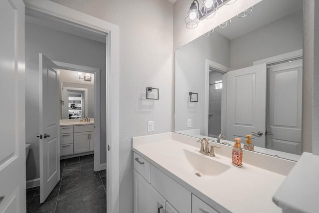 bathroom with tile patterned flooring, a textured wall, and vanity