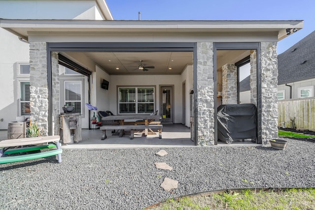 rear view of house with stone siding, covered porch, ceiling fan, and stucco siding