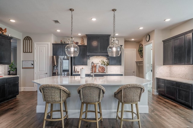 kitchen featuring light countertops, stainless steel refrigerator with ice dispenser, dark wood finished floors, and visible vents