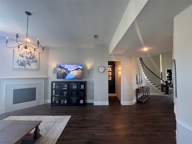 living area with wood finished floors, a fireplace, a textured ceiling, and stairs