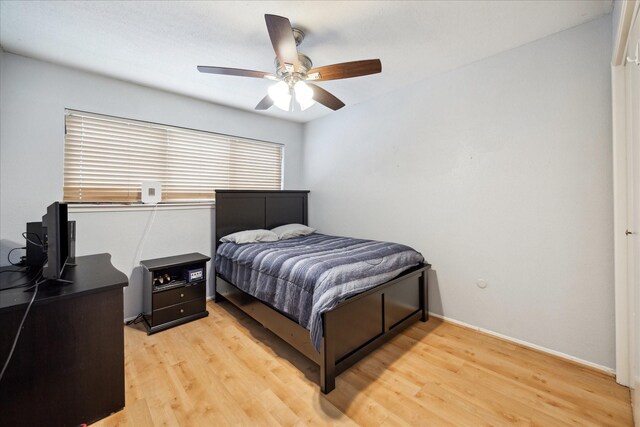 bedroom featuring light wood-type flooring, baseboards, and a ceiling fan