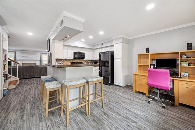 kitchen featuring black appliances, open floor plan, wood finished floors, an office area, and a peninsula