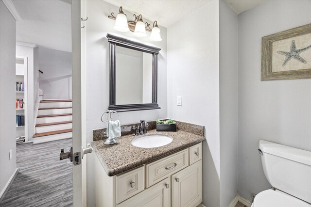 bathroom with toilet, baseboards, wood finished floors, and vanity