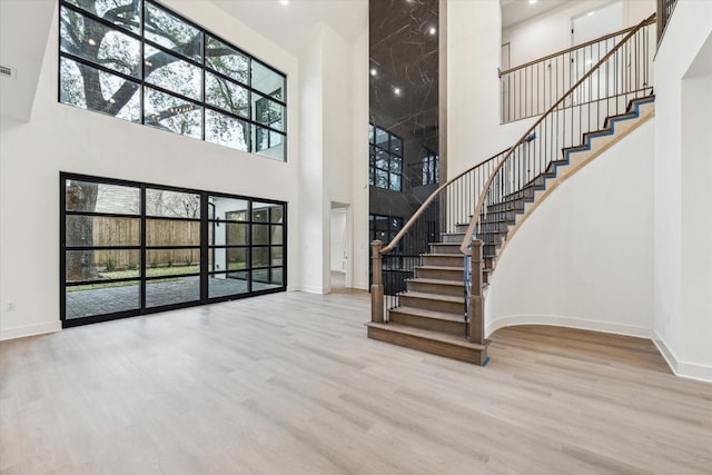 unfurnished living room featuring light wood-type flooring and a high ceiling