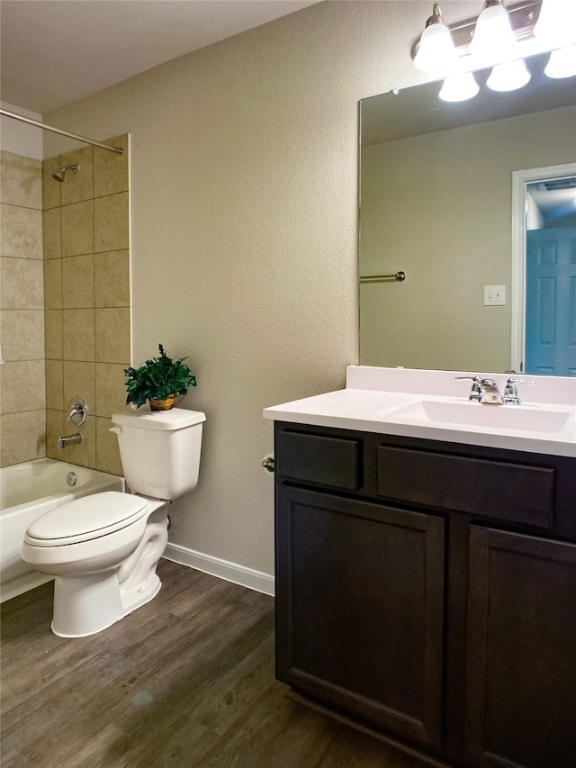 full bathroom with toilet, hardwood / wood-style flooring, tiled shower / bath, and vanity