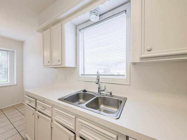 kitchen with sink, white cabinets, a wealth of natural light, and light tile patterned floors