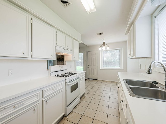 kitchen featuring sink, gas range gas stove, white cabinets, and pendant lighting