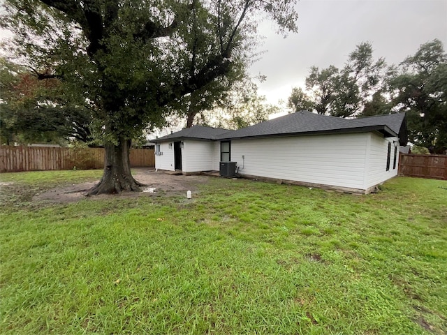 back of house featuring central AC unit and a lawn