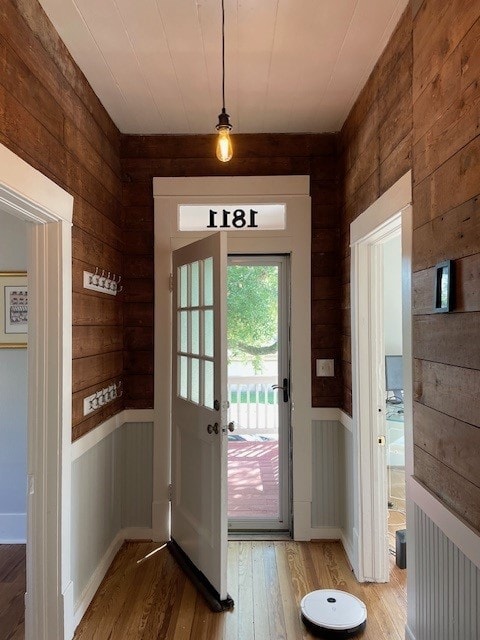 doorway featuring wooden walls and wood-type flooring