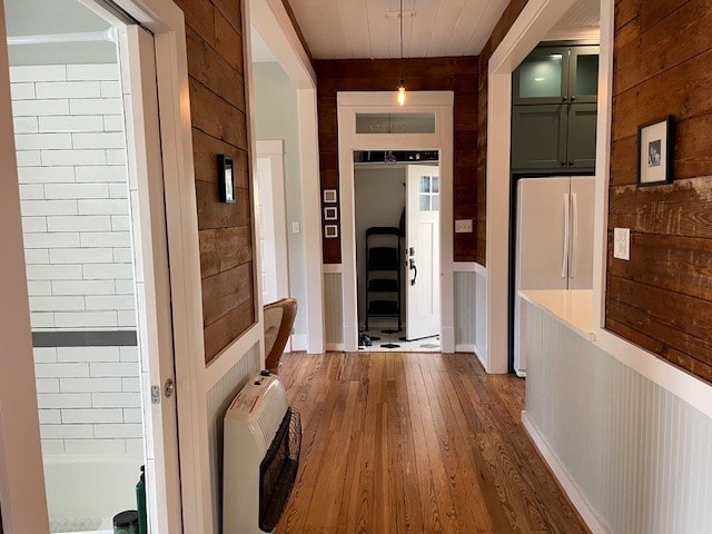 corridor with heating unit, dark hardwood / wood-style flooring, and wood walls